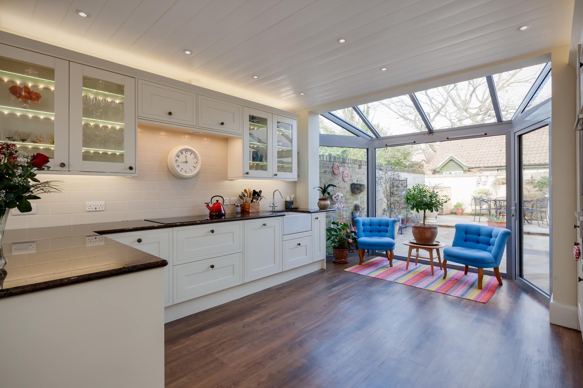 Schüco residential doors Striking modern kitchen in a fashionable traditional style with two blue armchars and large window leading to rear garden and patio.