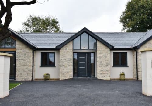 aluminium front doors in a stone-built new house with gable window above